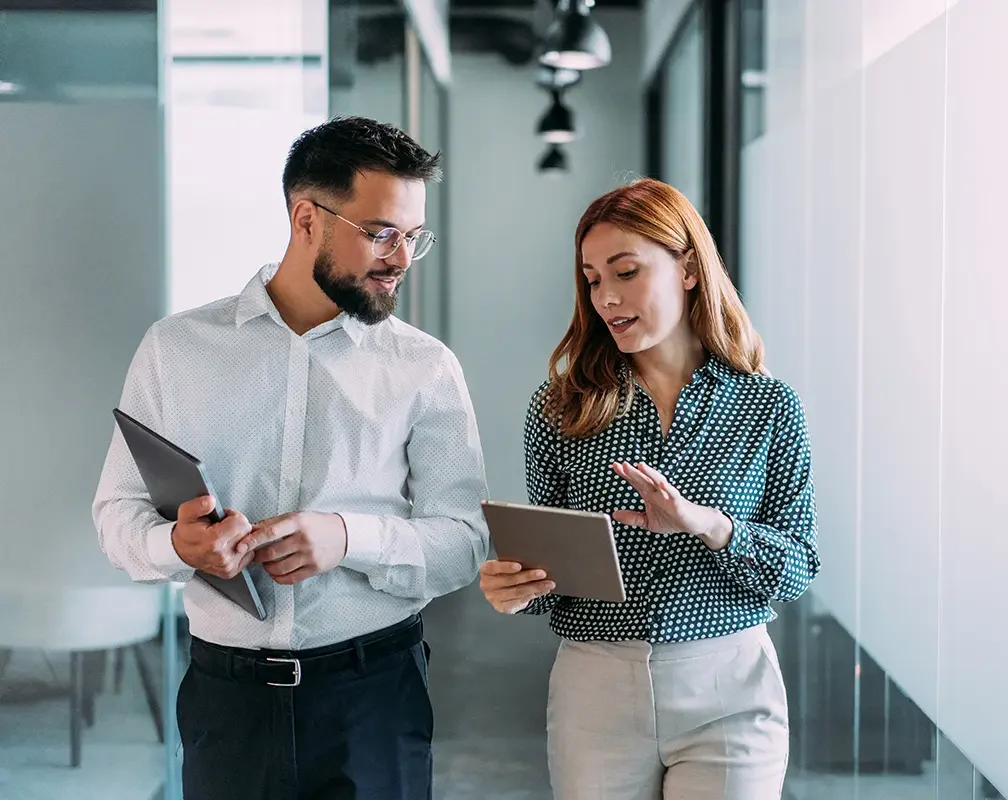 Interimsmanagement - Mann und Frau laufen auf einem Bürogang
