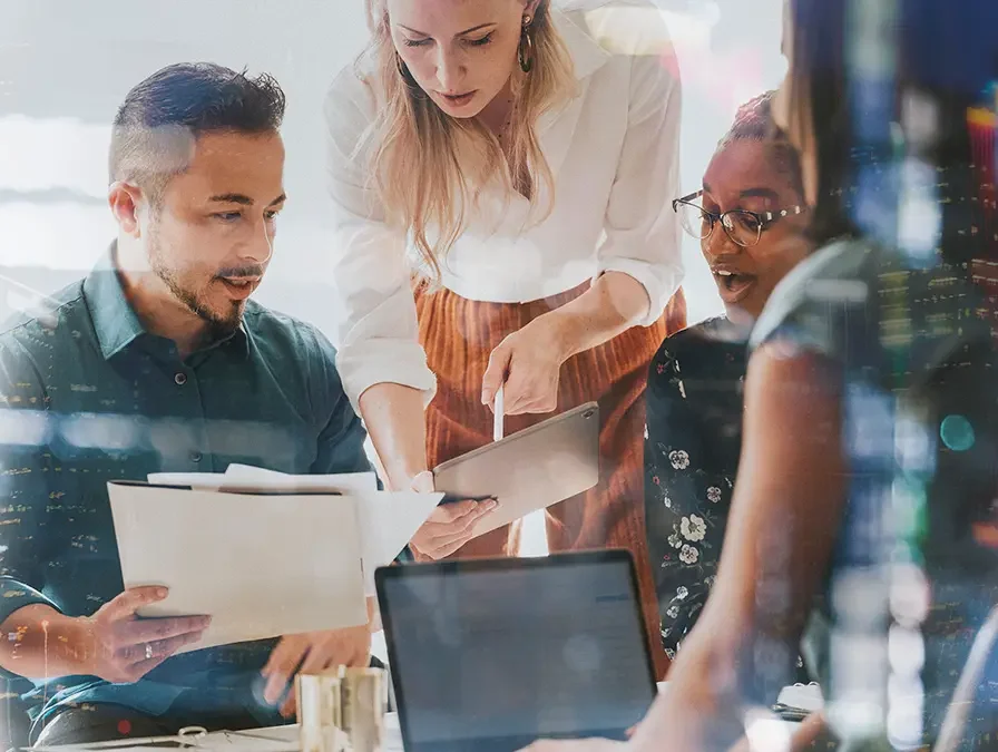 Wachstums-Strateige: Mehrere Menschen sitzen an einem Schreibtisch und schauen sich Dokumente an.
